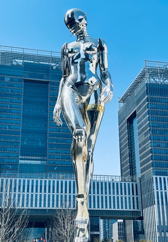 gallery-1 Modern chrome statue set against Shanghai's urban architecture, showcasing futurism.